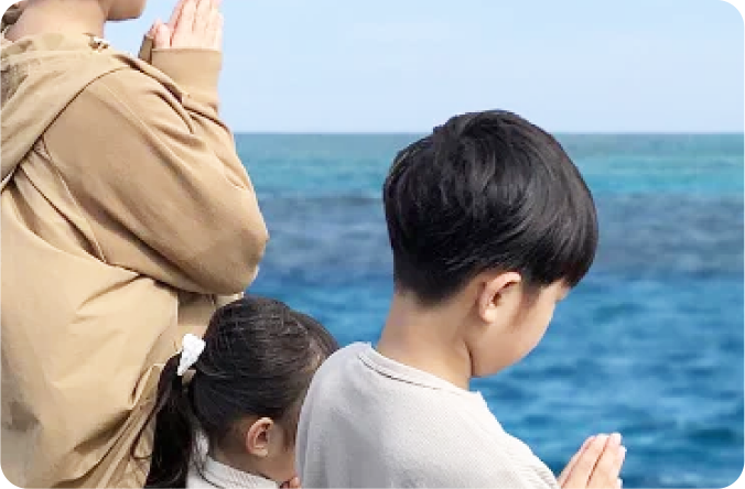 家族が海に手を合わせる写真